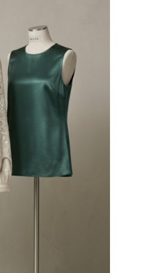 A sleeveless deep jade satin shell displayed on a dress form.